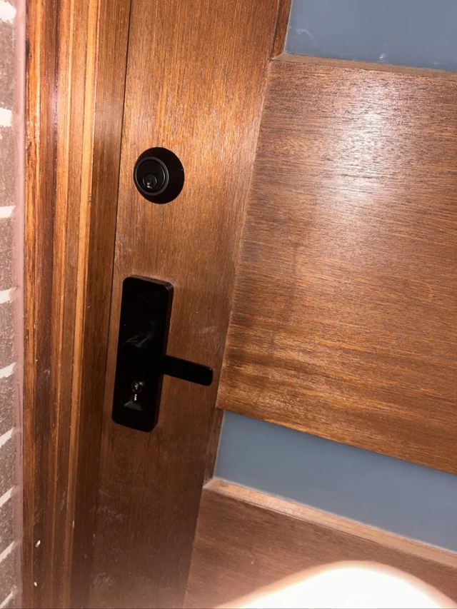 Black entrance set and peephole on a timber front door